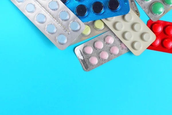 Pills in packages on a blue background, flat lay, copy space, close-up.