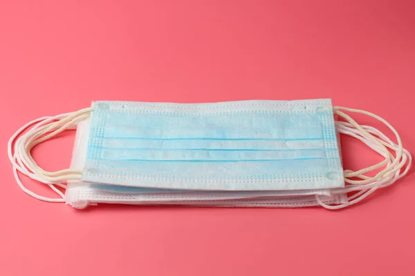 A stack of medical masks on a pink background close-up, flat lay, the concept of the fight against coronovirus and other infectious diseases.