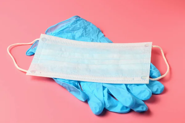 Medical gloves and mask on a pink background, protection against flu Covid-19 or other viruses and infections, concept.