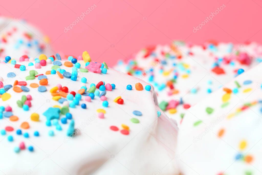 Sweet icing with colored sugar balls, stars, Pink background, copy space, close-up. Christmas or birthday concept, festive mood