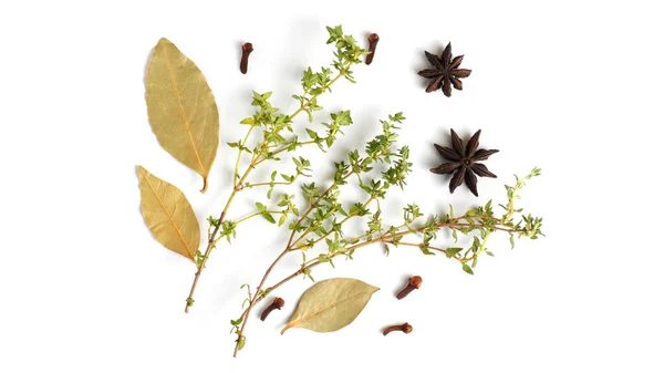 Fragrant herbs and spices on a white background. Bay leaf, cloves, allspice, thyme. Flat lay, top view, copy space.