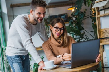 Kahve dükkanında dizüstü bilgisayar kullanan mutlu arkadaşlar