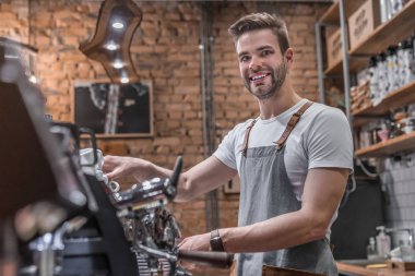 Kafeteryada kahve yapan genç bir barista.