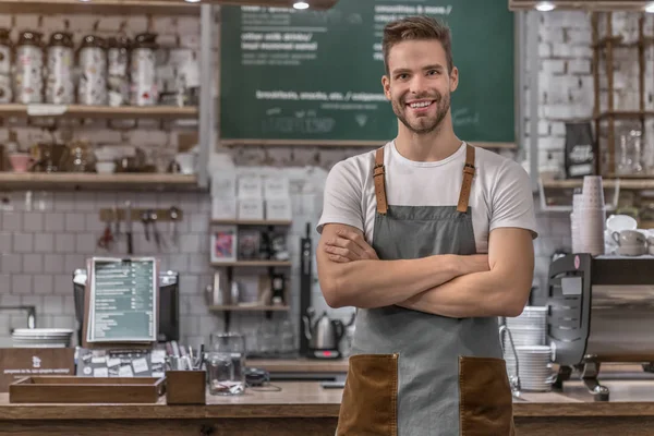 Portrait of smiling male coffee shop owner standing at the counter with look in camera — Stock Photo, Image