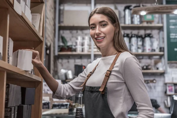 Jonge glimlachende vrouw barista nemen koffie sorteren in de winkel voor de klant — Stockfoto