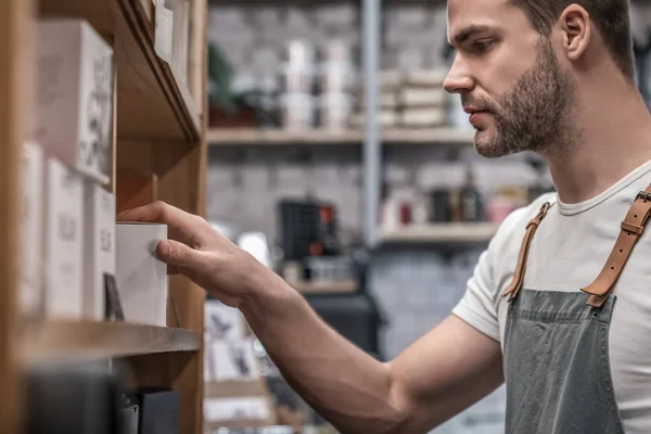 Young barista choosing coffee sort at shop for customer — Stock Photo, Image