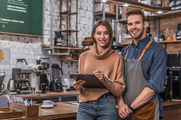 Small business smiling partners standing together at their coffee shop — Stock Photo, Image