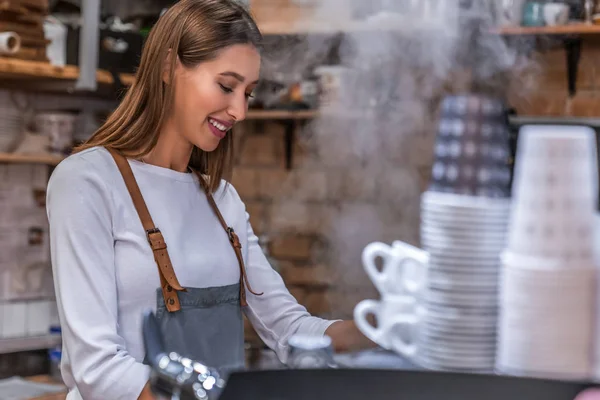 Female shop worker in his coffee shop wearing an apron. — Stock Photo, Image