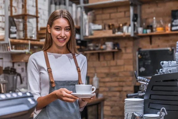 Portré mosolygós barista kezében csésze kávé a kávézóban — Stock Fotó