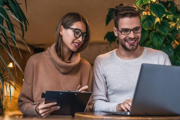 Deux jeunes hommes d'affaires travaillant sur ordinateur portable dans un café — Photo