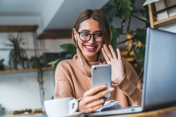 Jeune femme souriante vidéo bavardage à l'aide d'écouteurs et téléphone mobile . — Photo