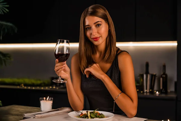 Portrait of beautiful young woman with glass of luxury red wine indoors — ストック写真