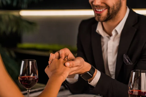Oříznutý obraz muže, jak dává zásnubní prsten na ženský prst během romantické večeře — Stock fotografie
