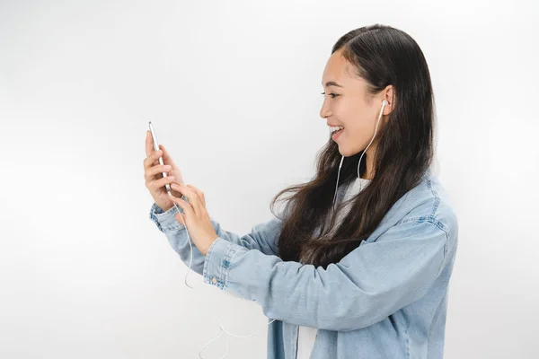 Mujer joven sobre fondo blanco aislado usando móvil con auriculares — Foto de Stock