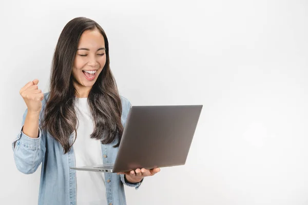 Porträt einer Frau, die lässig ihren Sieg ausdrückt, während sie Laptop auf weißem Hintergrund isoliert benutzt — Stockfoto