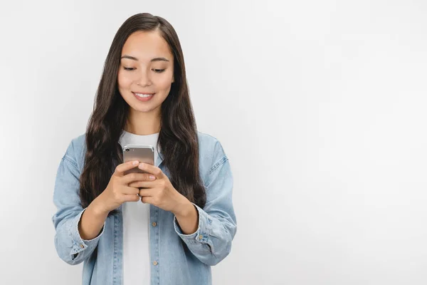 Retrato de mujer asiática joven sonriente usando teléfono móvil aislado sobre fondo blanco — Foto de Stock
