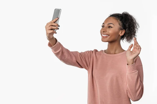 Mujer africana vistiendo ropa casual tomando selfie y saludando de la mano en un teléfono inteligente aislado sobre fondo blanco con espacio para copiar — Foto de Stock