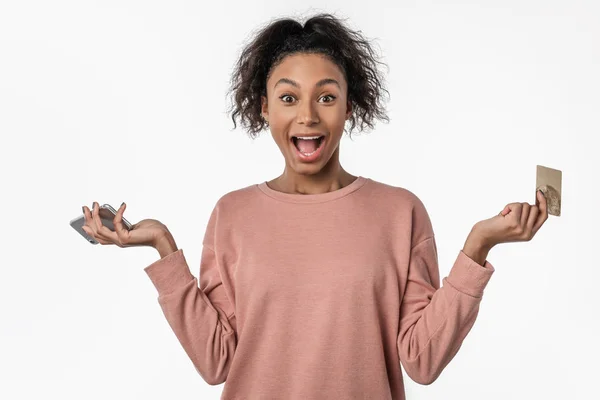 Vacker chockad kvinna som innehar kreditkort och mobiltelefon över vit bakgrund — Stockfoto