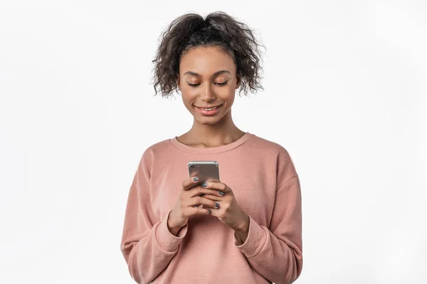 Glad ung afro amerikansk kvinna som använder mobiltelefon när du står isolerad över vit bakgrund — Stockfoto