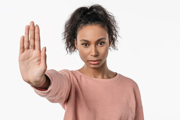 Portrait of serious young african woman showing stop gesture with her palm isolated over white background — Stock Photo, Image