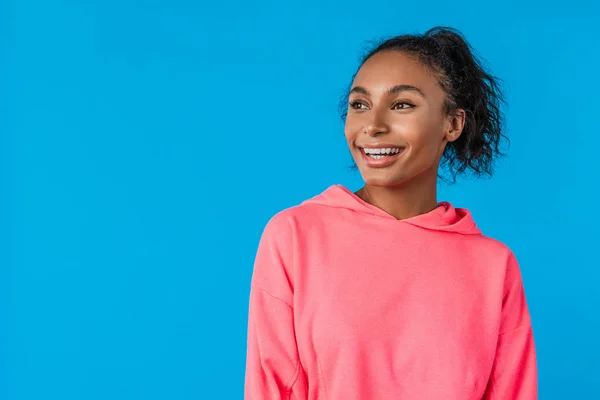 Jovem mulher africana atraente com penteado afro sorrindo sobre fundo azul — Fotografia de Stock