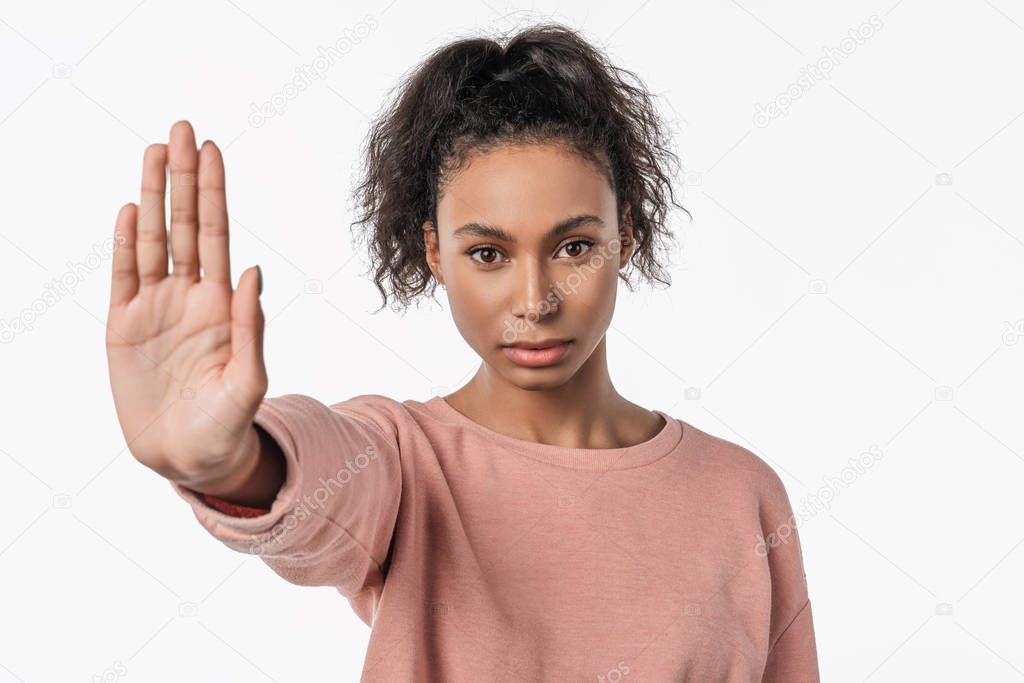Portrait of serious young african woman showing stop gesture with her palm isolated over white background