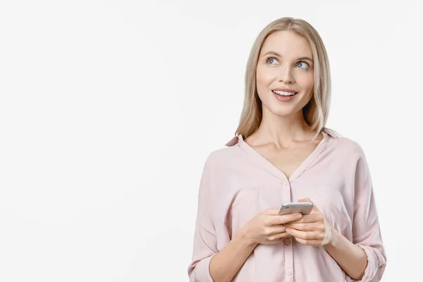 Attraktivt tänkande ung blond kvinna poserar isolerad över vit bakgrund med hjälp av mobiltelefon — Stockfoto