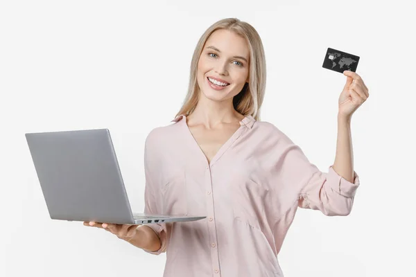 Glædelig ung kvinde ved hjælp af bærbar computer viser kreditkort isoleret over hvid baggrund - Stock-foto