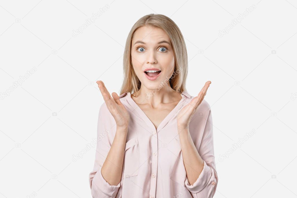 Portrait of young surprised woman with opened mouth standing with open palms isolated on white background