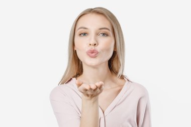 Genç ve çekici bir kadının hava öpücüğü gönderip beyaz arka planda izole edilmiş kameraya baktığı yakın plan.