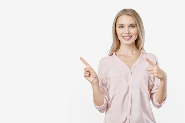 Donna sorridente che punta lontano e guardando in macchina fotografica su sfondo bianco — Foto Stock