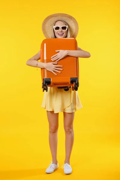 垂直ショットの若いです女性以上隔離された黄色の背景で休暇で旅行スーツケース — ストック写真