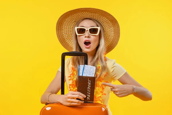 Fiatal meglepett nő izolált sárga háttér nyaralás bőrönddel és útlevéllel — Stock Fotó