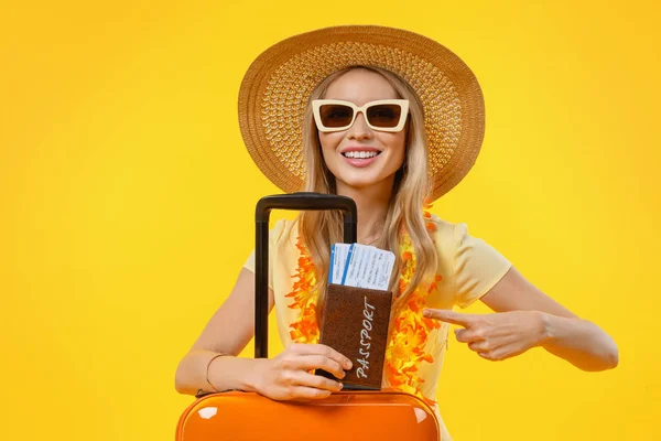 Nő megy nyaralni bőrönddel és útlevéllel rámutatva elszigetelt sárga háttér — Stock Fotó
