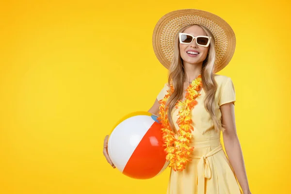 Bella donna con accessori da spiaggia tenendo palla colorata su sfondo giallo — Foto Stock