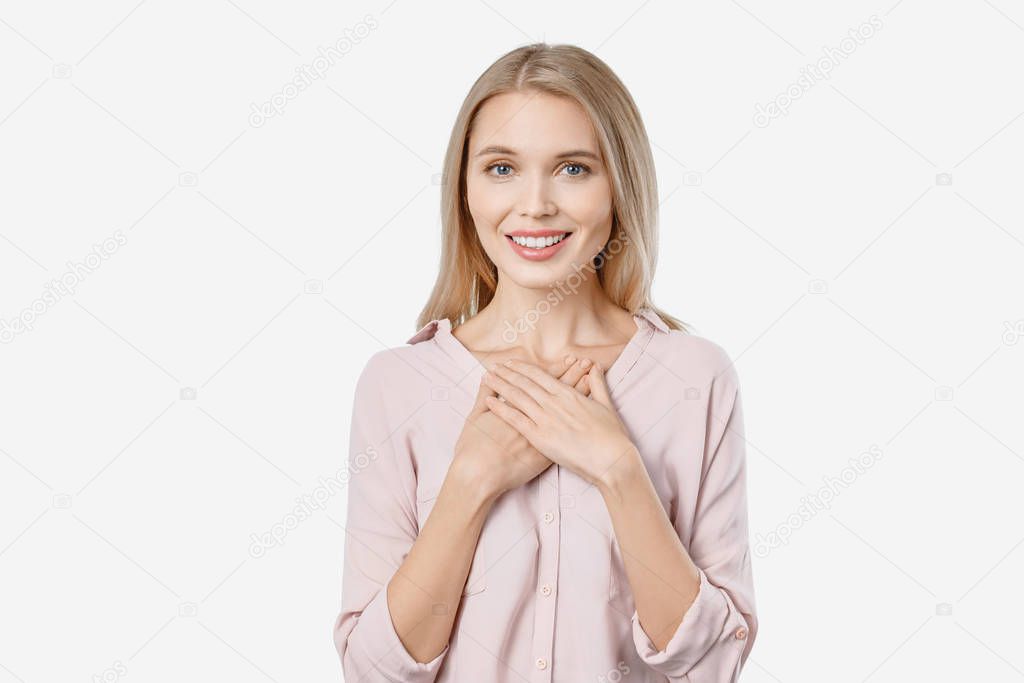 Friendly looking young female holding hands crossed on her chest expressing gratitude saying thanks