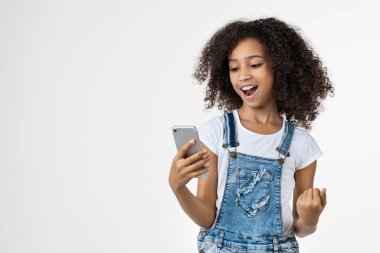Cep telefonu kullanan mutlu Afrikalı genç kız beyaz arka planda yalnız poz veriyor.