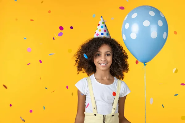 Engraçado pequena senhora no evento de festa de aniversáriocom balão e confete caindo isolado no fundo amarelo — Fotografia de Stock