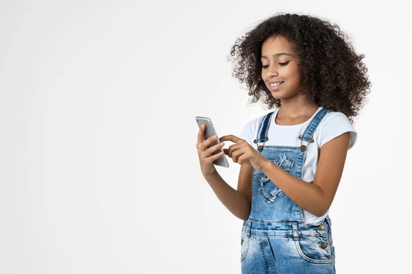 Pequena menina pré-adolescente alegre usando telefone celular isolado no fundo branco — Fotografia de Stock
