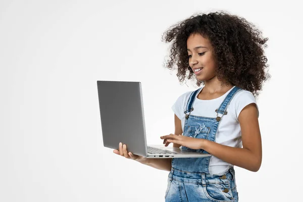 Portret uśmiechniętej dziewczynki korzystającej z laptopa stojącej na białym tle — Zdjęcie stockowe