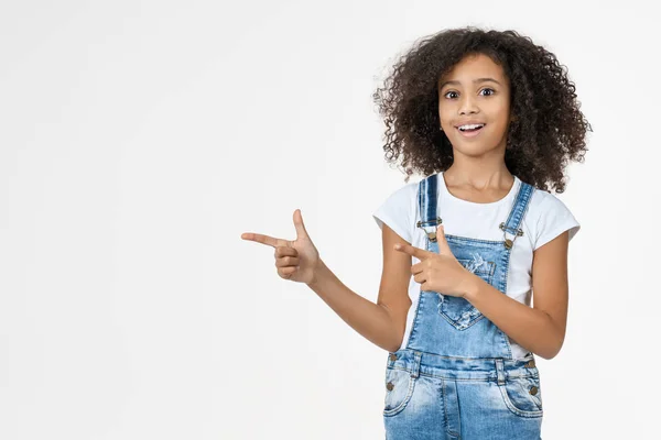 Adorable linda niña africana apuntando en el espacio de copia en el estudio fondo blanco — Foto de Stock