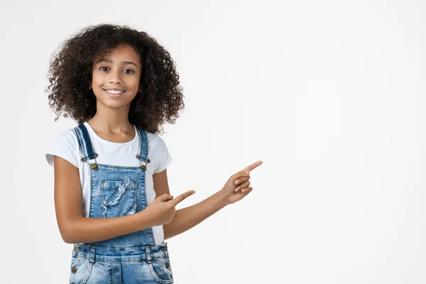 Heureuse fille afro-américaine pointant les doigts de côté à l'espace de copie isolé sur fond blanc — Photo
