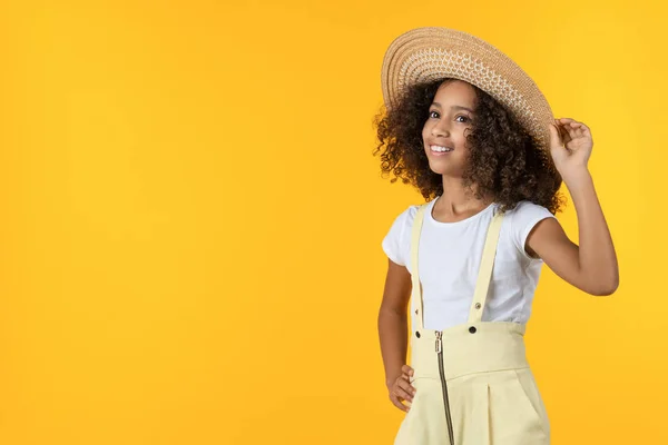 Cute african american little girl in straw hat smiling isolated over yellow background — ストック写真