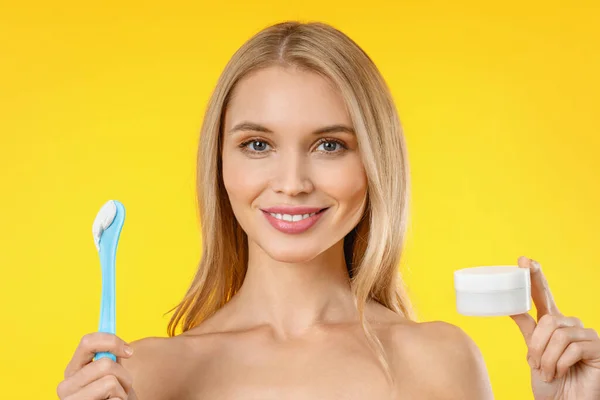 Portrait of smiling beautiful woman holding skin cream over yellow background — 스톡 사진