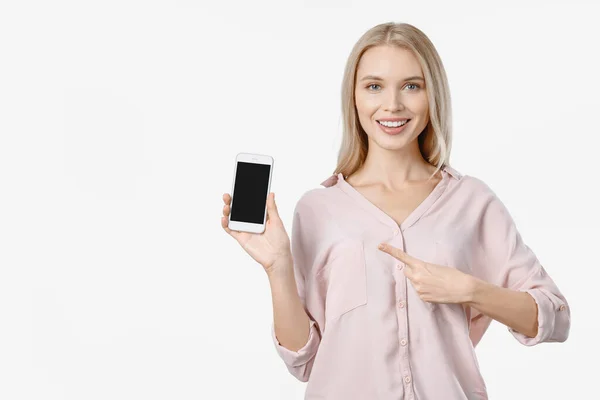 Улыбающаяся женщина, указывающая на смартфон, стоящий на белой спине — стоковое фото