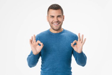 Portrait of smiling young man showing okay gesture isolated on white background