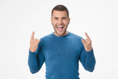 Young man showing rock sign while listening music isolated on white background