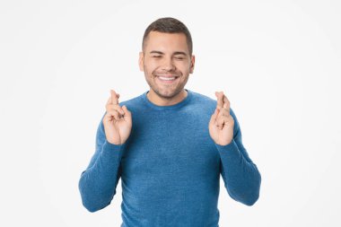 Young handsome man over isolated background with fingers crossing making a wish