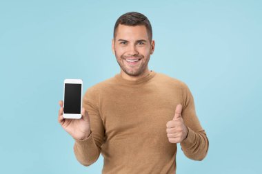 Happy young man with smartphone and showing ok gesture