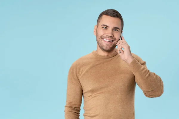 Cheerful young man in casual talking on mobile phone posing isolated on blue background — 스톡 사진